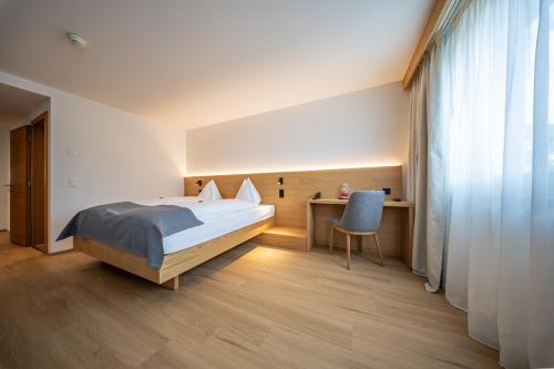 a bedroom with a bed and a desk with a chair at Hotel Piz St. Moritz in St. Moritz