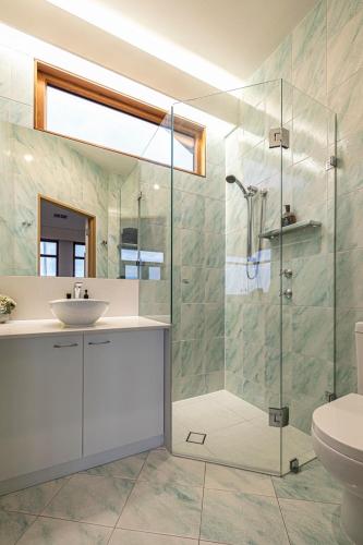 a bathroom with a glass shower and a sink at Seascape At Tennyson Beach in Grange