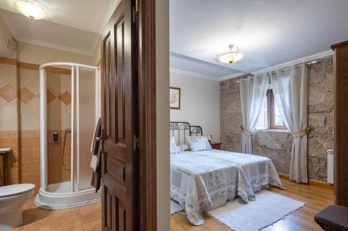 a bedroom with a bed and a shower and a toilet at Casa Rural Magina in Fornelos de Montes