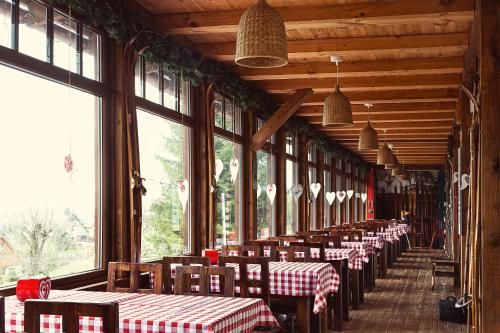 Una fila de mesas y sillas en una habitación con ventanas. en Absolwent, en Duszniki-Zdrój