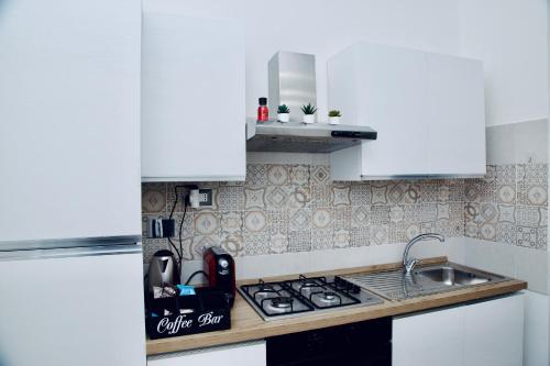 a kitchen with white cabinets and a stove top oven at Casa Amare Aeroporto Fiumicino in Focene
