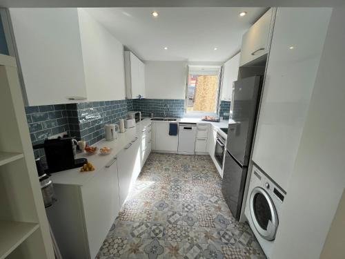 une cuisine avec des armoires blanches et un sol carrelé dans l'établissement Hyper centre - à 100m de la plage et 250m du casino, à Trouville-sur-Mer