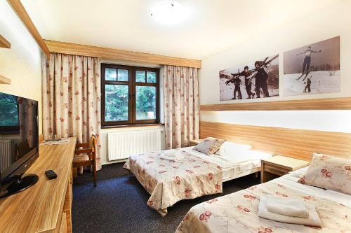 Una habitación de hotel con dos camas y un televisor. en Absolwent, en Duszniki-Zdrój