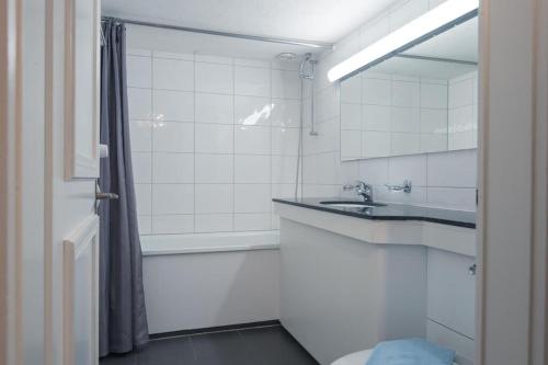 a white bathroom with a sink and a shower at HITrental Chapel Bridge Apartments in Luzern