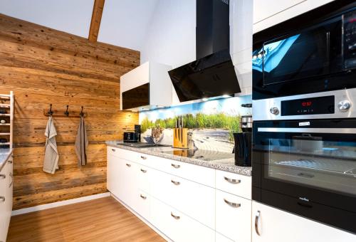 a kitchen with white cabinets and a stove top oven at Ferienhaus Ankerplatz mit Sauna in Strandnähe in Reinberg