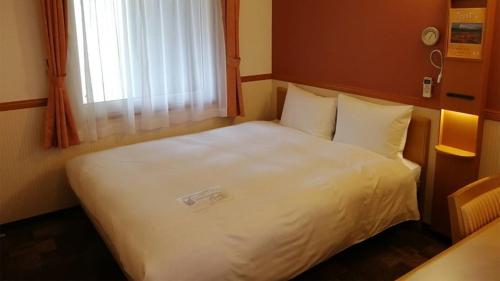 a white bed in a small room with a window at Toyoko Inn Tokyo Yamanote sen Otsuka eki Kita guchi No 2 in Tokyo