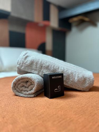 - une serviette sur un lit avec un panneau de bienvenue à côté dans l'établissement Le Pantaléon - Sublime Studio Capitole, à Toulouse
