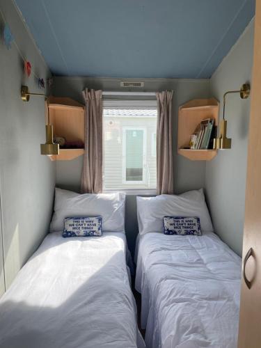 two beds in a small room with a window at Ecco Lodge Caravan in Leysdown-on-Sea