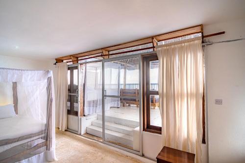 a bedroom with a bed and a glass window at Shimoni Reef Lodge in Shimoni