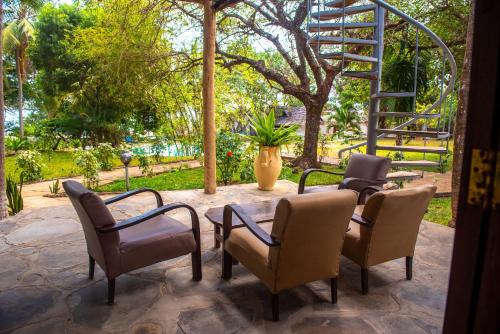 a patio with chairs and a table and a ladder at Shimoni Reef Lodge in Shimoni