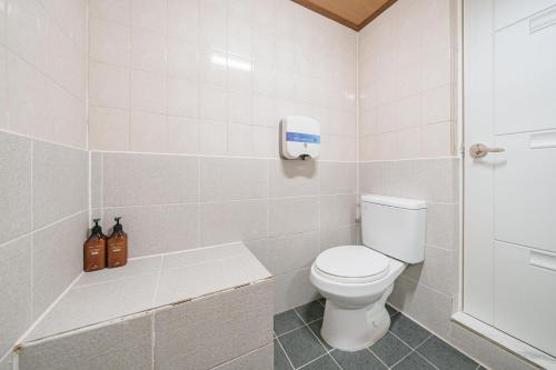 a white bathroom with a toilet and a shower at Jeju Miracle Hotel in Jeju