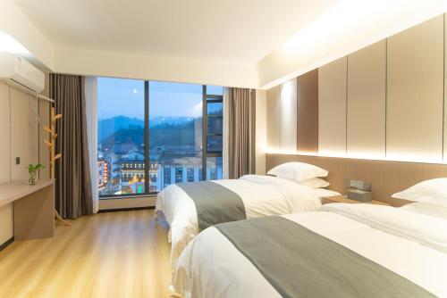 a hotel room with two beds and a large window at Lucky Praised Scenery Hotel in Zhangjiajie