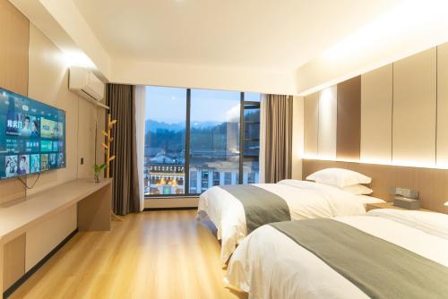 a hotel room with two beds and a flat screen tv at Lucky Praised Scenery Hotel in Zhangjiajie