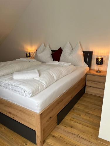 a large bed with white sheets and pillows on it at Apartments und Zimmervermietung in Liesingthal