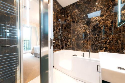 a bathroom with a tub and a sink and a mirror at Fountain House Apartments - London in London