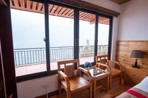 a room with a table and chairs and large windows at SaPa Retreat Condotel in Sa Pa