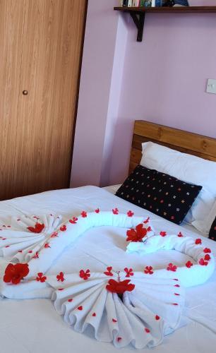 a bed with white sheets with red flowers on it at Palm garden paradise in Pervolia