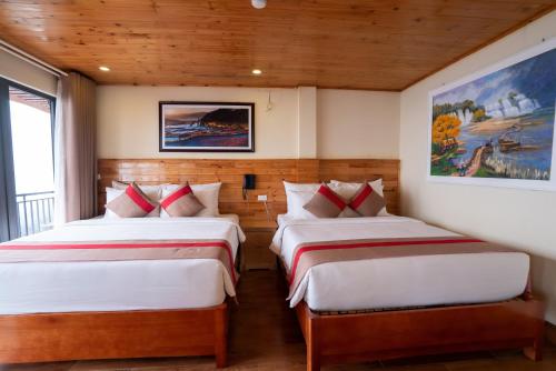 two beds in a room with wooden walls at SaPa Retreat Condotel in Sa Pa