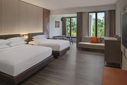a hotel room with two beds and a couch at Palm Garden Hotel, Putrajaya, a Tribute Portfolio Hotel in Putrajaya