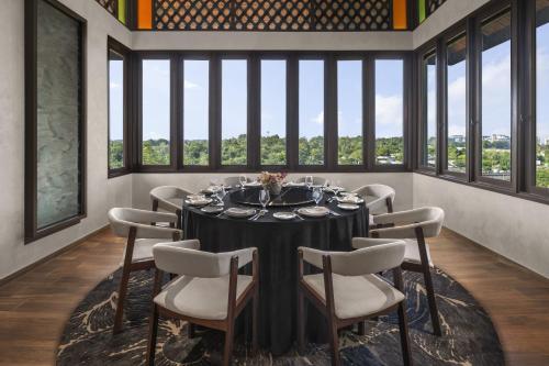 a dining room with a table and chairs and windows at Palm Garden Hotel, Putrajaya, a Tribute Portfolio Hotel in Putrajaya