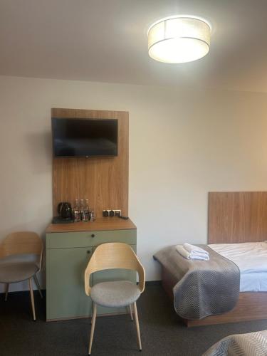 a bedroom with a bed and a chair and a table at Hotel Carskie Koszary in Zamość