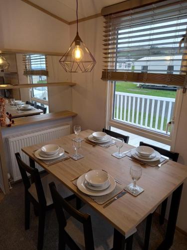 a wooden table with chairs and plates and wine glasses at 35 Beach Grove - Craig Tara in Ayr