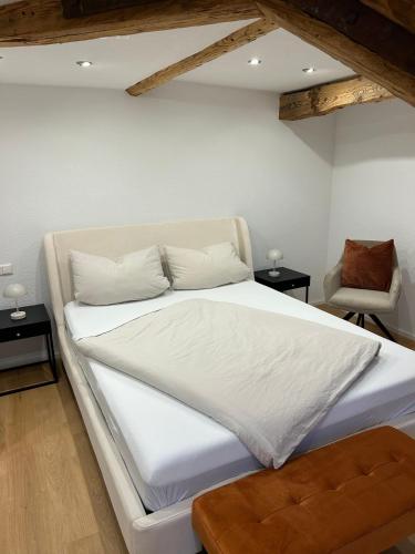 a bedroom with a white bed and a chair at Erholungsloft in Bad Buchau