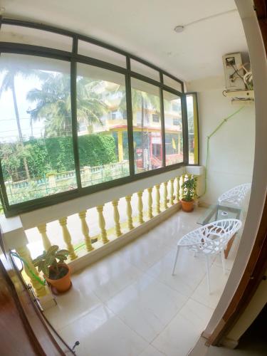 a room with a balcony with a chair and a window at Rajbag Residency Guest House in Canacona