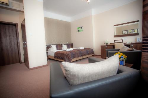 a living room with a bed and a couch at Hotel & SPA Odeon in Boguchwała