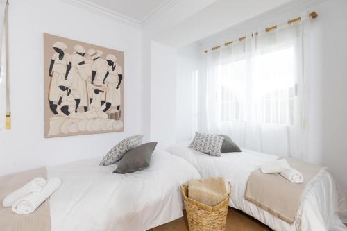 two beds in a white room with a picture on the wall at Fidalsa Divine Hiding in Algorfa