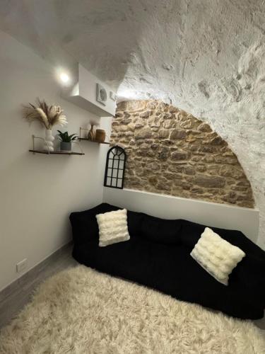a black couch in a room with a stone wall at L’Eden Centre ville in Melun