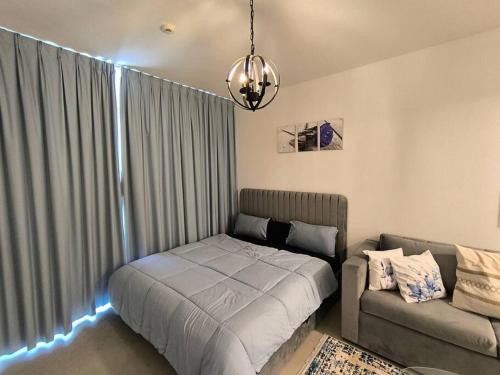 a bedroom with a bed and a couch and a chandelier at Venus saadiyat beach apartment with SeaView in Abu Dhabi