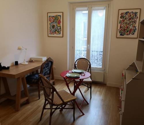 une cuisine avec une table, des chaises et une table ainsi qu'une salle à manger dans l'établissement Charmant appartement parisien 2 pièces, à Paris