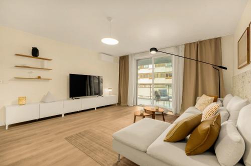 un salon avec un canapé blanc et une télévision dans l'établissement Savana - apt à 10min du Capitole, à Toulouse