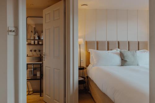 a bedroom with a large white bed and a kitchen at No 15 by GuestHouse, Bath in Bath