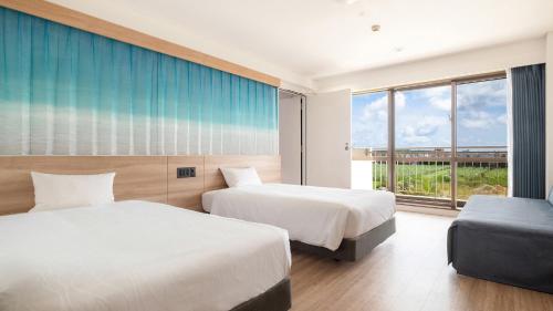 a hotel room with two beds and a window at Watermark Hotel Okinawa Kume Island in Kumejima