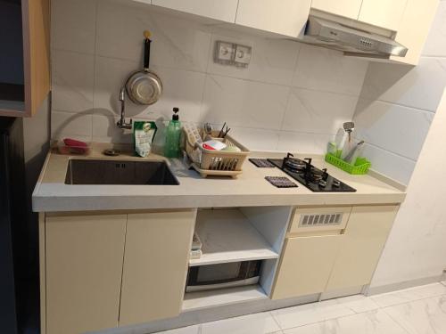 a small kitchen with a sink and a stove at Apartemen Sky House BSD in Cilenggang