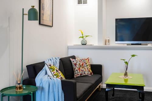 a living room with a couch and a tv at Hobart Retreat with City and Water View in West Hobart