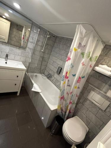 a bathroom with a toilet and a shower curtain at Boutique-garni Hotel Papillon in Kempen