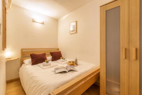 - une chambre avec un lit doté de draps blancs et d'oreillers bruns dans l'établissement Le Bellevue 05 - Happy Rentals, à Chamonix-Mont-Blanc