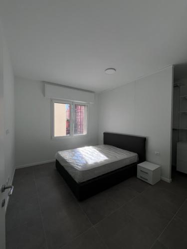 a white bedroom with a bed and a window at Dealuna Motel in Fidenza