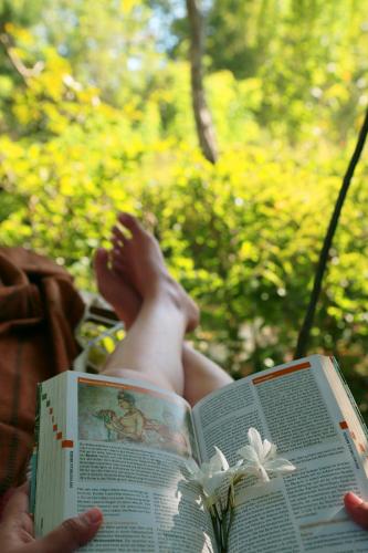 a person laying down reading a book with their feet up at The Cattleya Guest House Sigiriya in Sigiriya