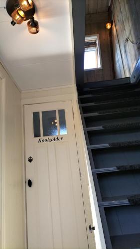 a hallway with a door and stairs with a sign on it at De oude walnoot in Sint Pancras