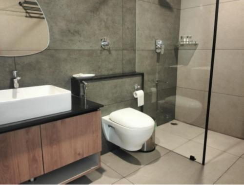Un baño con inodoro, lavabo y ducha. en Atmosfera Bengaluru, India, en Bangalore