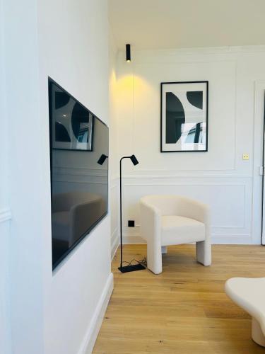un salon avec une chaise blanche et une lampe dans l'établissement Le Notre-Dame, mon appartement Cosy et Elegant, à Strasbourg