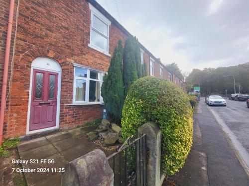 a brick house with a red door and a fence at Cosy cottage in Chorley