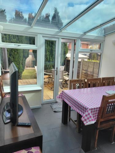 a conservatory with a table and a tv on a table at Cosy cottage in Chorley