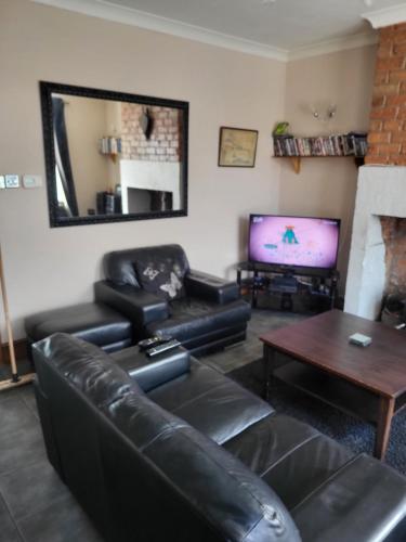 a living room with a leather couch and a tv at Cosy cottage in Chorley
