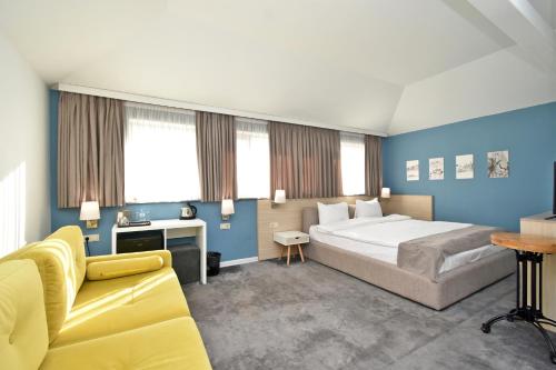 a bedroom with a large bed and a yellow couch at In City Hotel in Yerevan