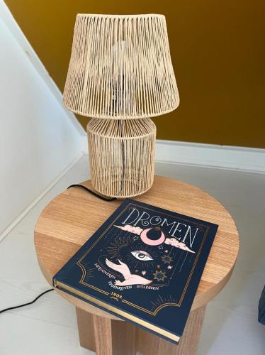 a table with a book and a lamp on it at B&B slaap in Buurse in Haaksbergen
